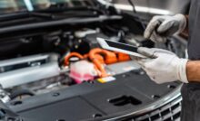 Mecânico usa tablet para controle de dados, representando a gestão integrada no setor automotivo.