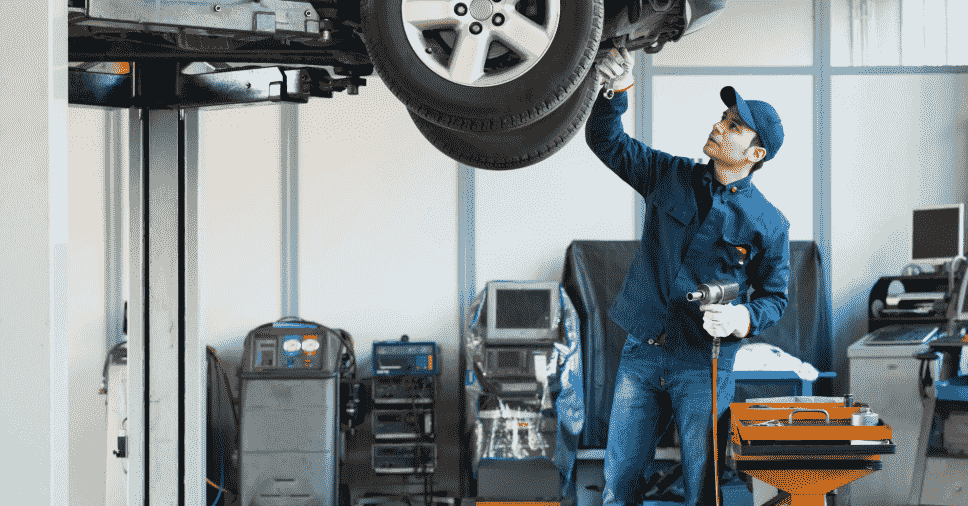 Profissional realiza manutenção em veículo suspenso, exemplificando a hora técnica x preço fixo.