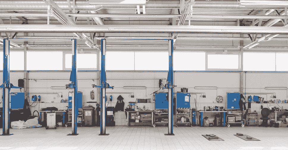 Visão panorâmica de um pátio da oficina com elevadores automotivos e bancadas de ferramentas.