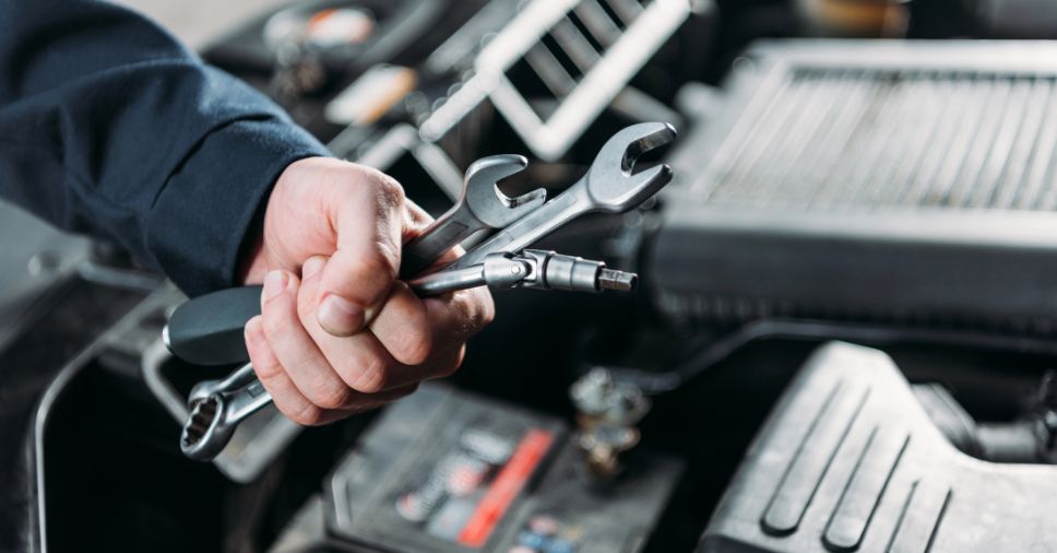 Mecânico segura chaves de boca em oficina para ilustrar a saúde financeira da oficina.