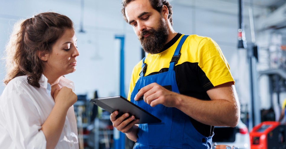 Mecânico atende motorista mostrando dados no tablet para exemplificar como atrair clientes.